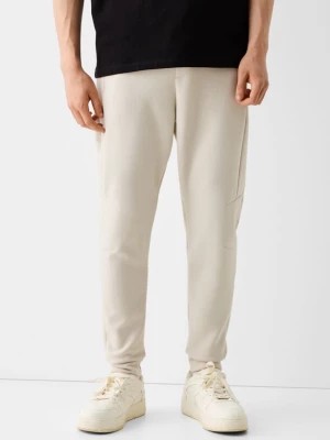 Zdjęcie produktu Bershka Spodnie Jogger Z Dzianiny Dresowej Z Widocznymi Szwami Mężczyzna Biały Złamany