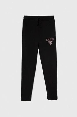 Zdjęcie produktu Guess spodnie dresowe bawełniane dziecięce kolor czarny z nadrukiem