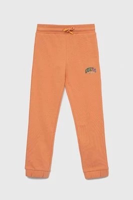 Zdjęcie produktu Guess spodnie dresowe bawełniane dziecięce kolor pomarańczowy gładkie