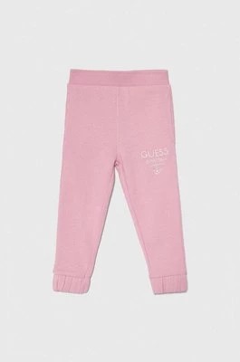 Zdjęcie produktu Guess spodnie dresowe bawełniane dziecięce kolor różowy z nadrukiem