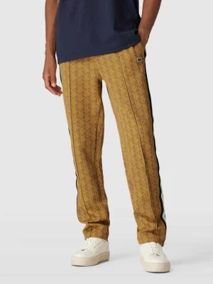 Zdjęcie produktu Spodnie sportowe o kroju regular fit ze wzorem na całej powierzchni i lampasami Lacoste