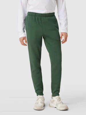Zdjęcie produktu Spodnie dresowe z paskami z logo model ‘TAPE’ Lacoste